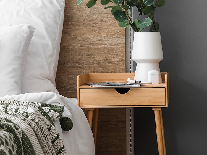 Modern style bedside table with a white vase holding greenery.